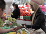 Woman buys strawberries at City Heights Farmers Market